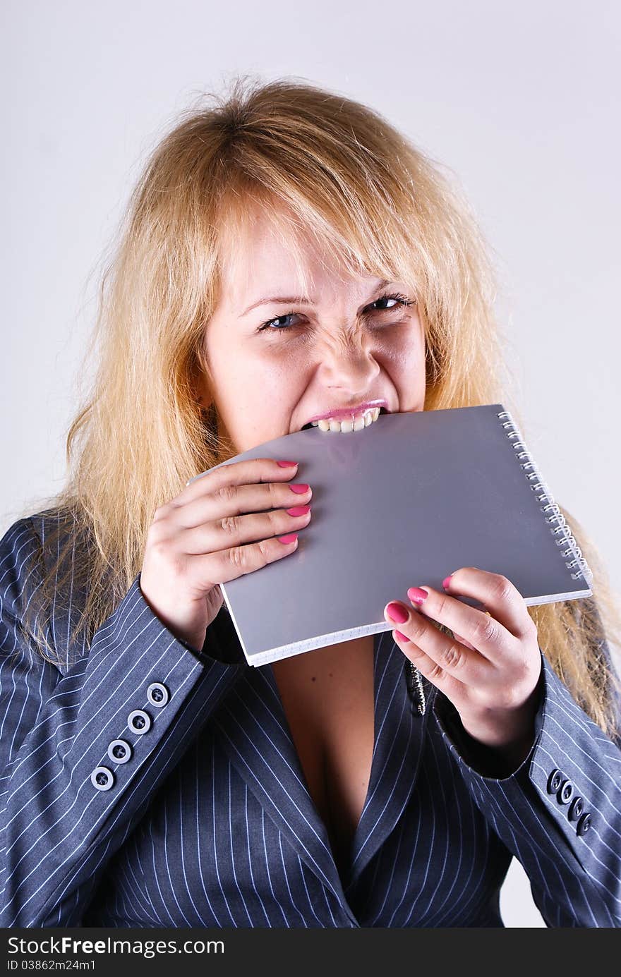 Girl gnaws a grey notebook on white