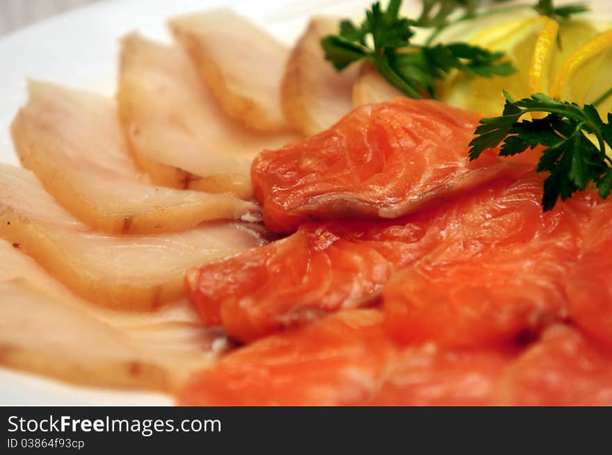 Slices of sturgeon and salmon with lemon and parsley