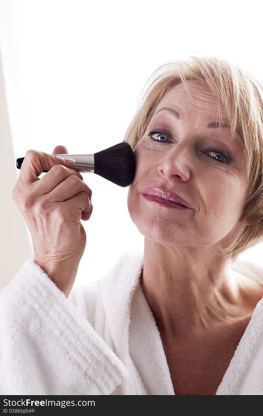 Mature Woman applying face powder. Mature Woman applying face powder