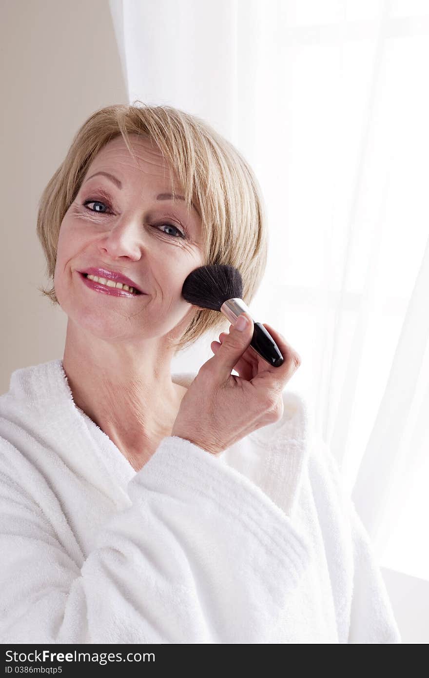 Mature Woman applying face powder. Mature Woman applying face powder