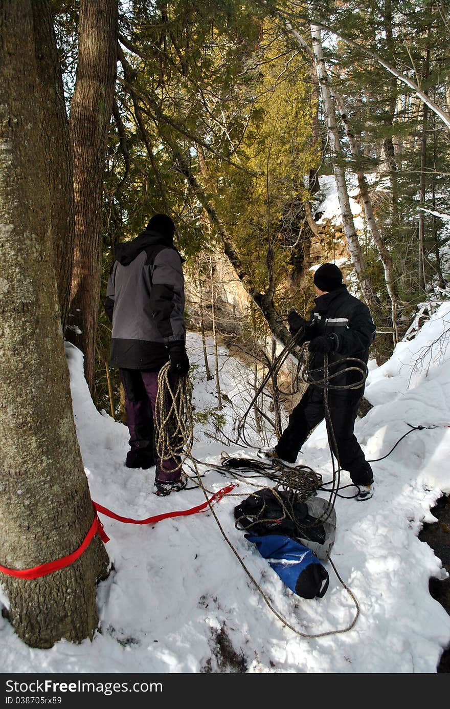 Two men setting up anchors for ice climbing. Two men setting up anchors for ice climbing.