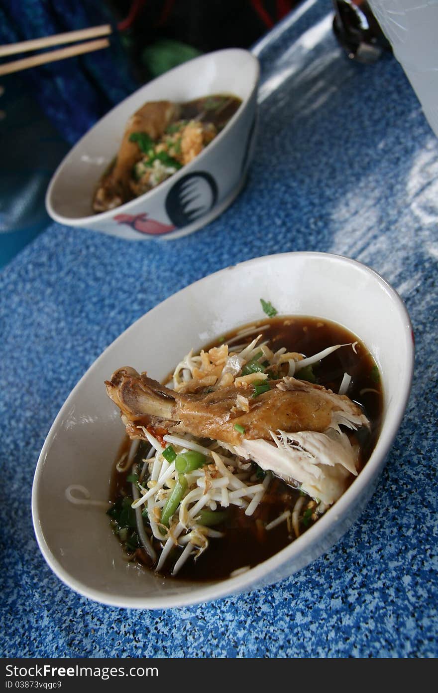 Image of thai soup with chiken on a white plate on a blue table