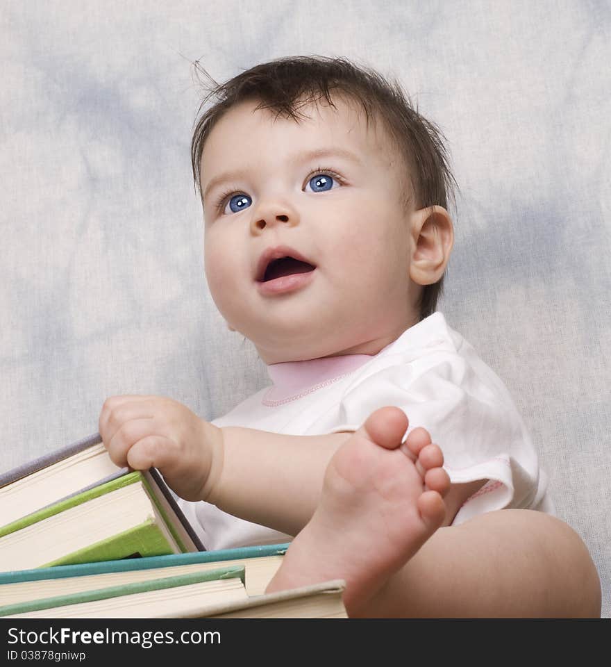 The small child with books on a light background