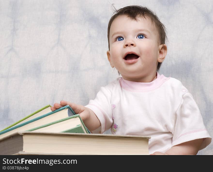 The small child with books on a light background