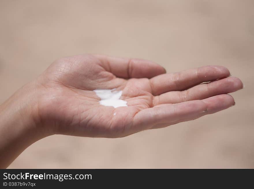 Sunblock on a female hand on the background of the beach. Sunblock on a female hand on the background of the beach