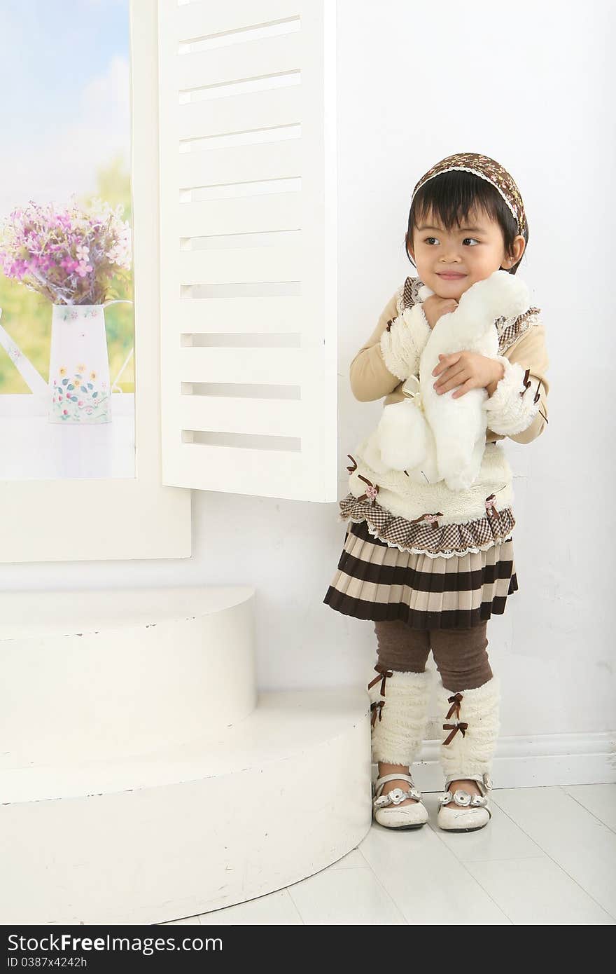 A lovely Chinese girl holding a toy against the window。