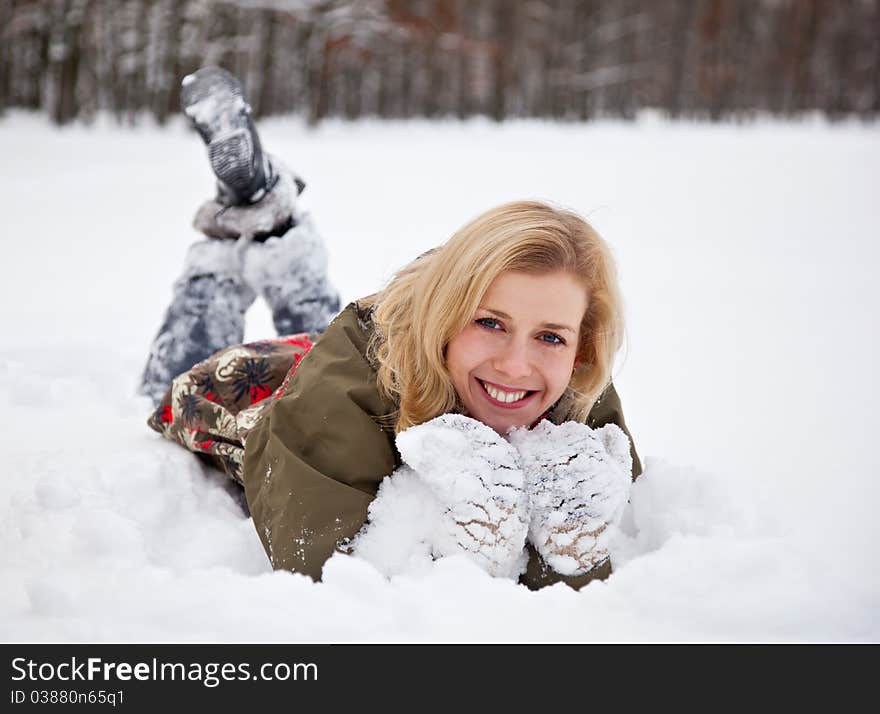 A woman is lying at the snow in the park