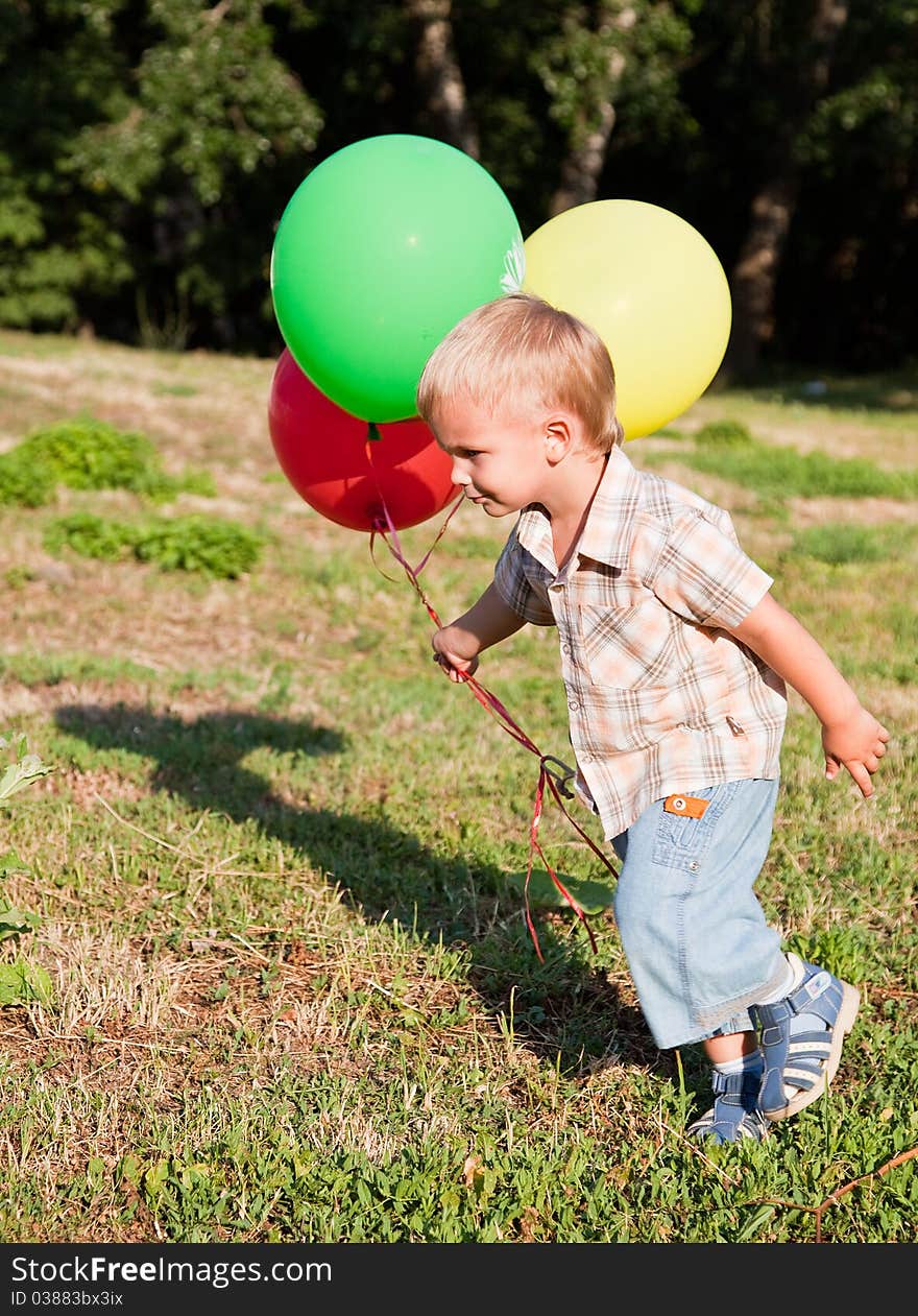 A Boy Is Standing On A Lawn With Colorful Balloons