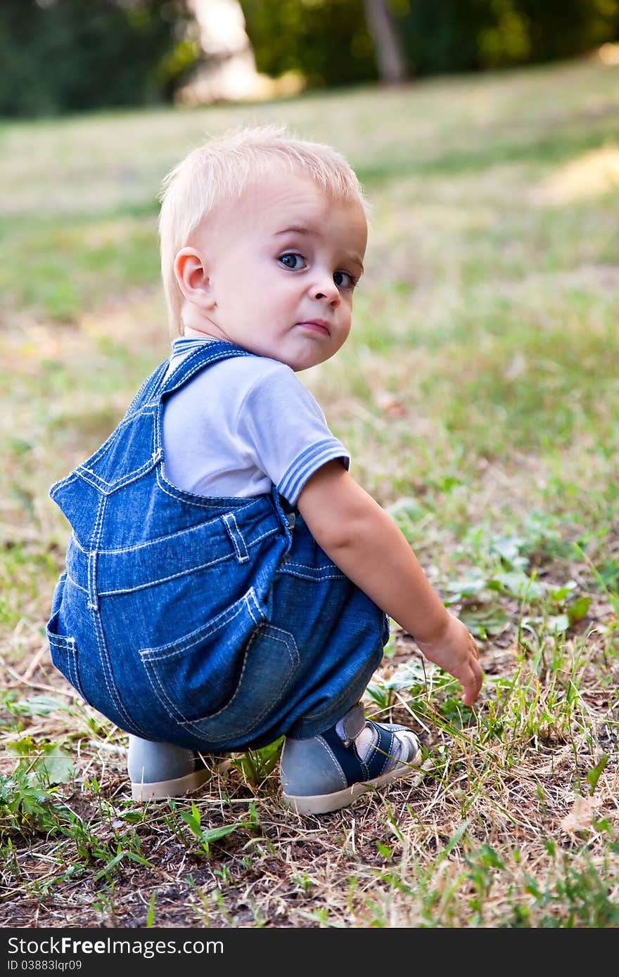 A boy is looking for something in the grass