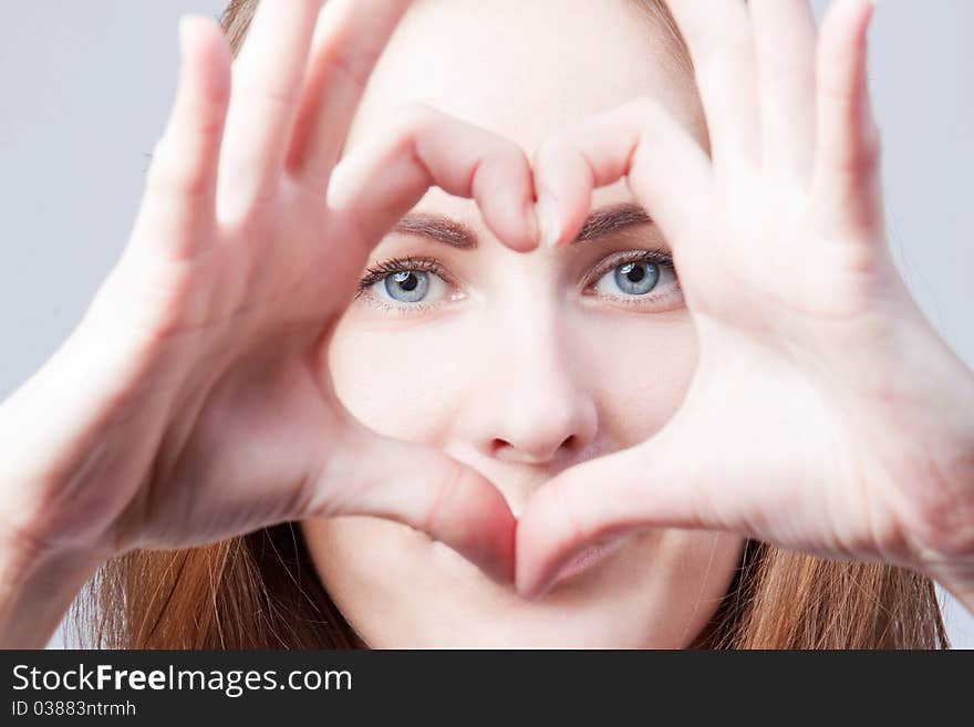 The beautiful girl shows heart from fingers