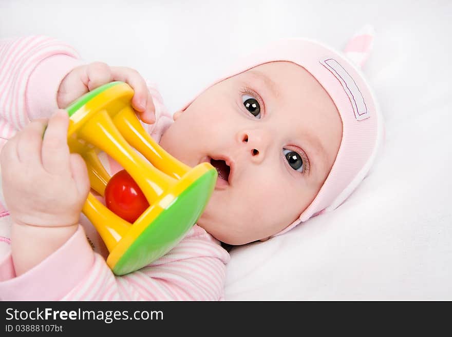 Closeup face of a beautiful newborn girl with rattle