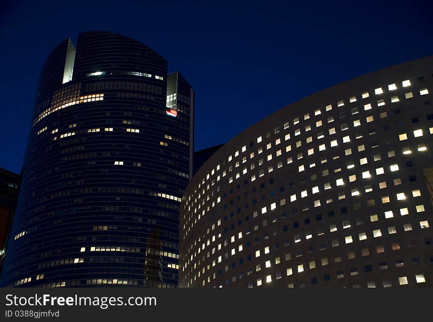 Skyline of modern skyscrapers with illuminated windows and dark sky during the night