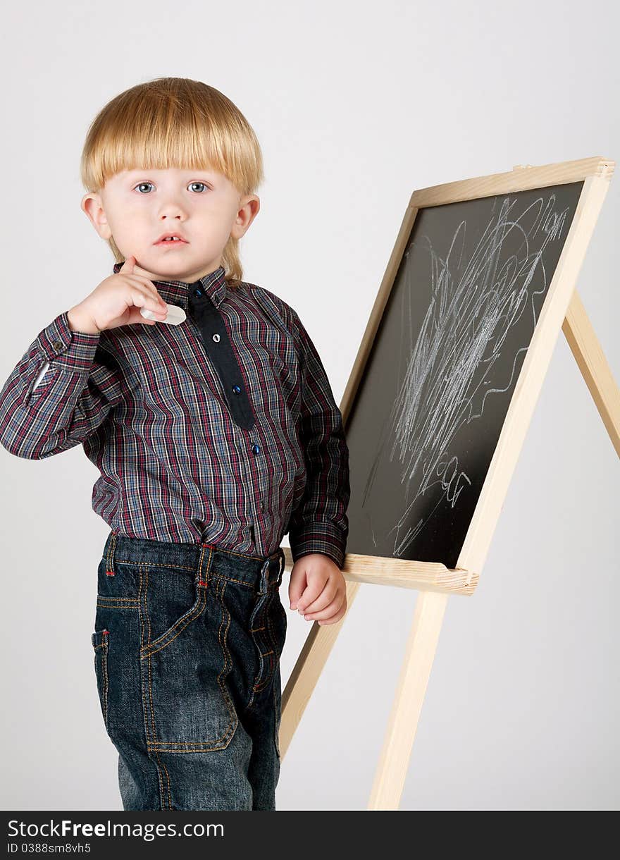 Little boy draws on blackboard