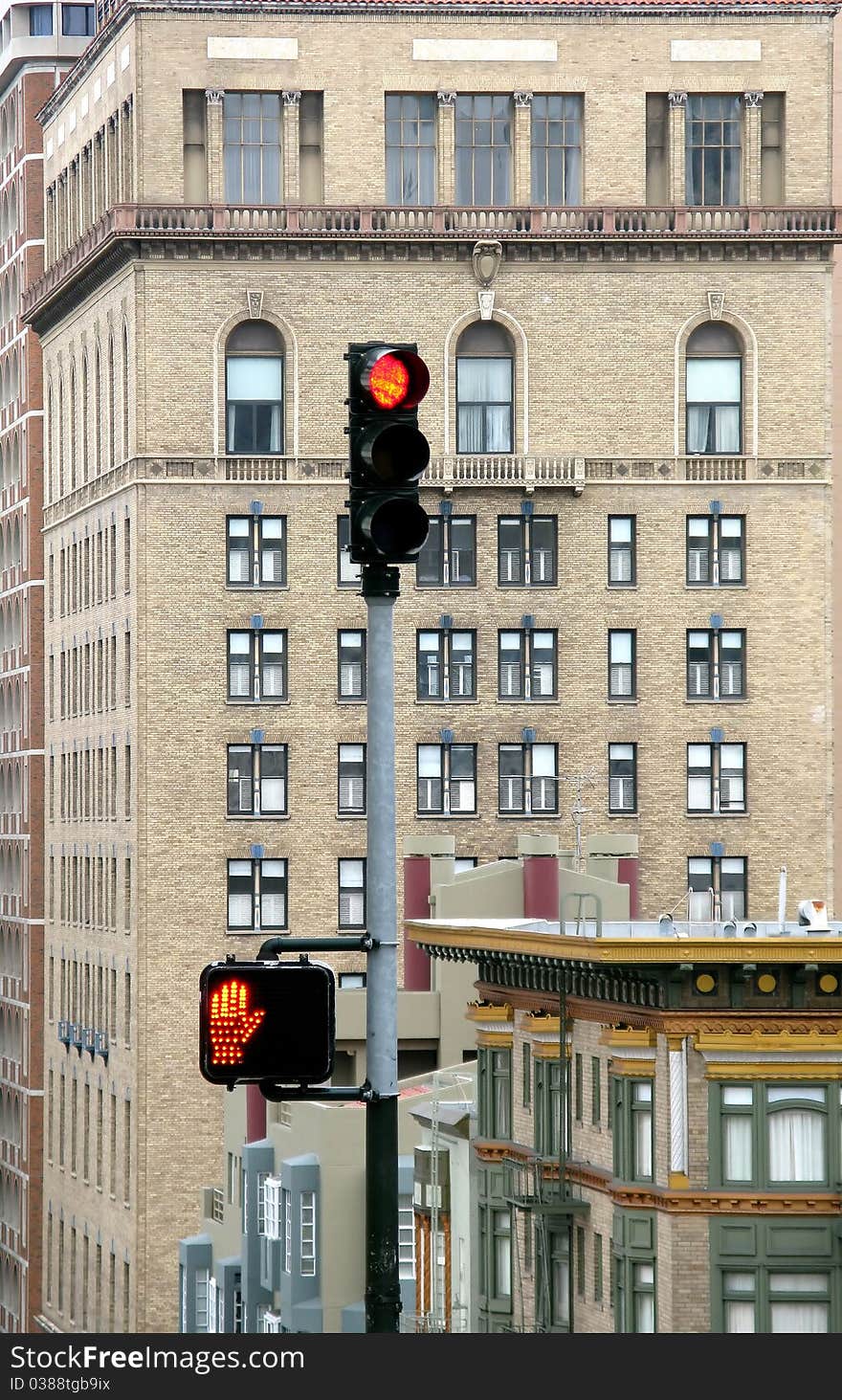 Details of an electric traffic light with a modern building in the background.