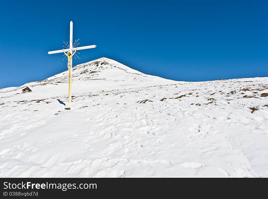 Christian cross with Jesus crucified in mountain landscape