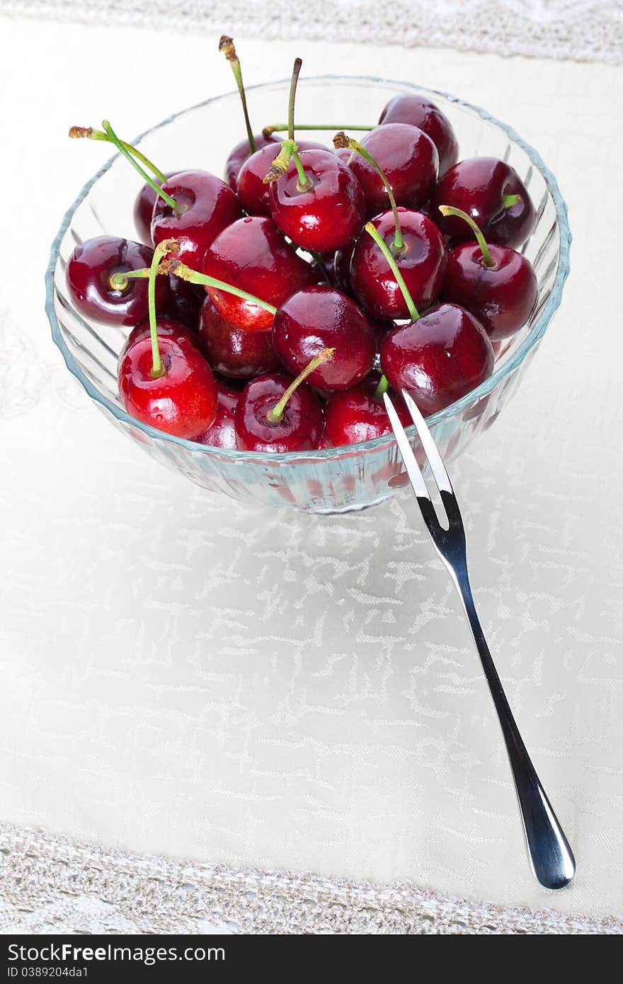 A bowl of fresh cherry with one fruit fork. A bowl of fresh cherry with one fruit fork.