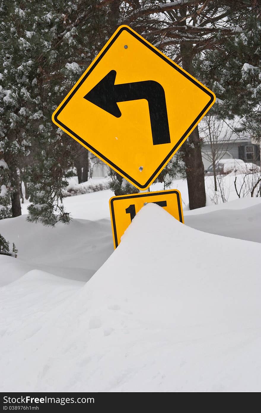 After a heavy snow storm a traffic sign is partially covered by snow. After a heavy snow storm a traffic sign is partially covered by snow.