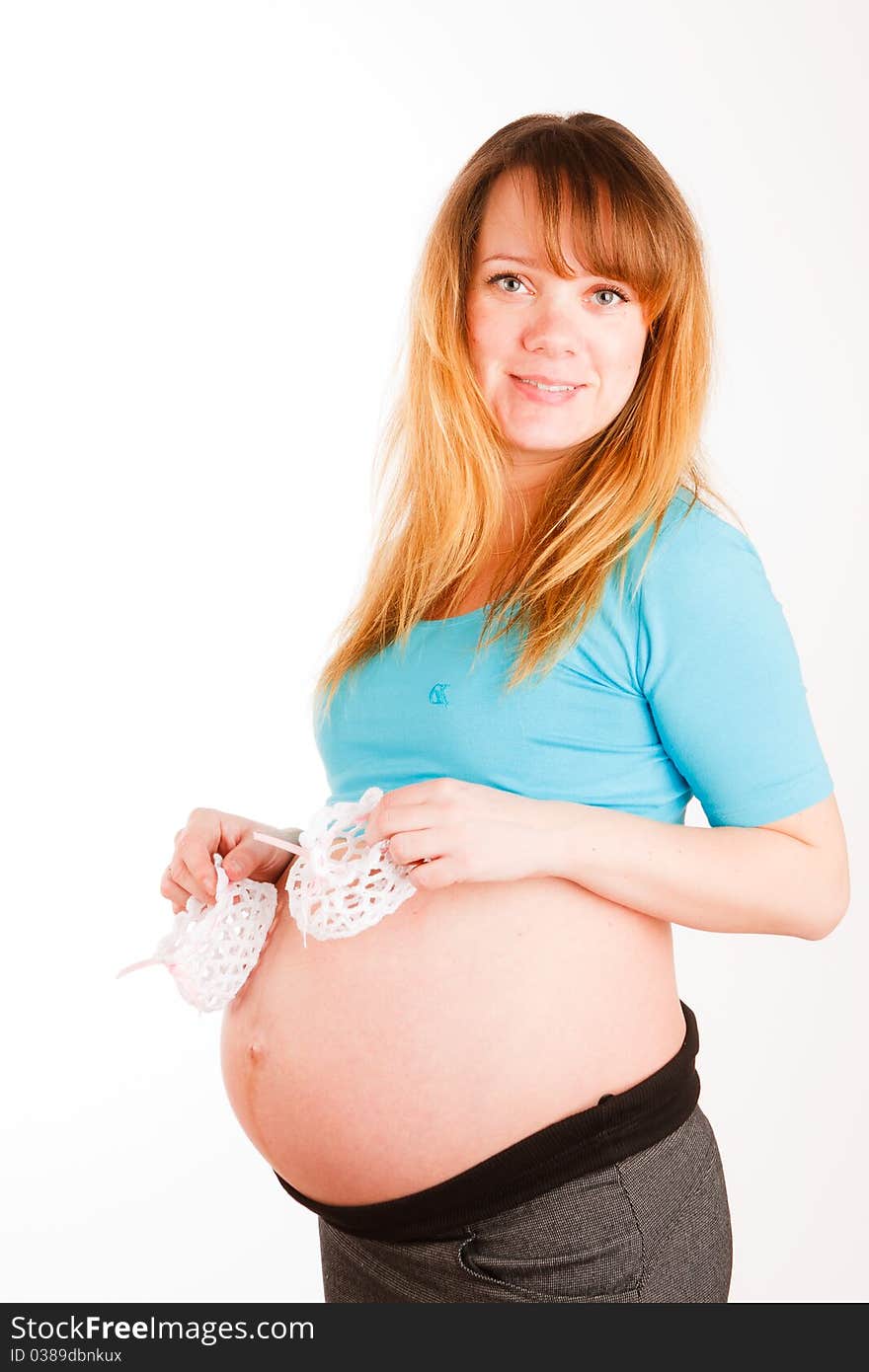 Beautiful pregnant woman with baby's bootees on white background