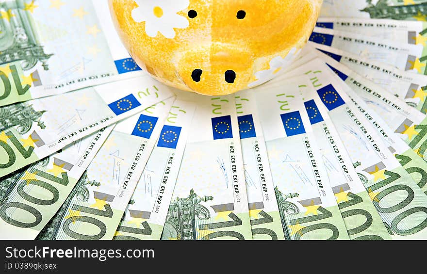 Yellow ceramic piggy bank on a pile of European banknotes. Yellow ceramic piggy bank on a pile of European banknotes