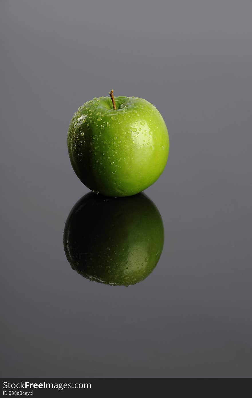 Green apple with reflection on a gray background