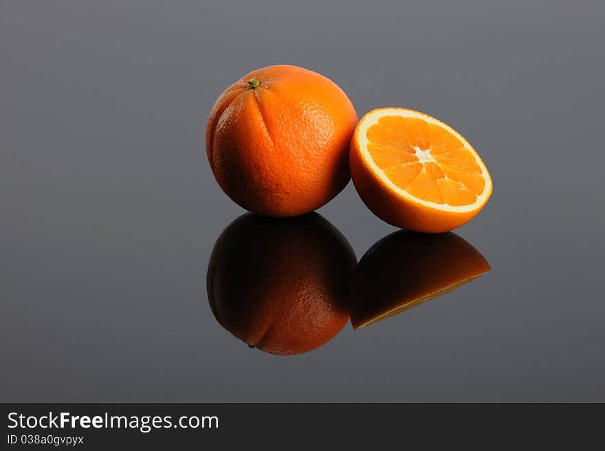 Oranges sitting on a shinny surface with reflection