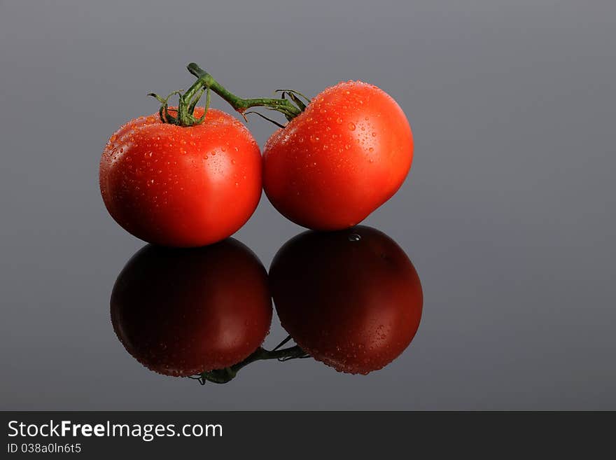 Two Red tomatoes on a reflecting gray surface