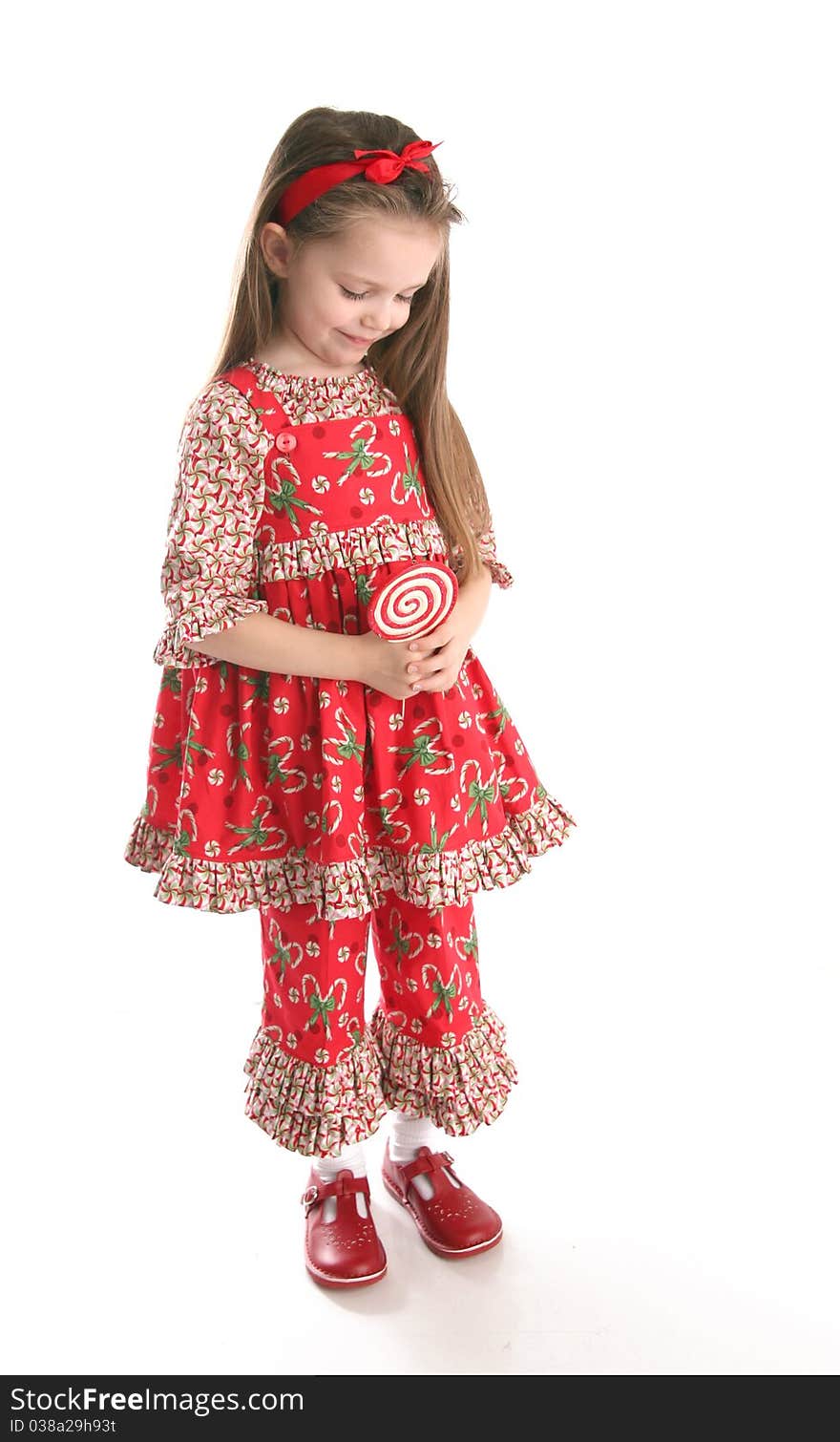 Adorable preschool girl wearing a Christmas holiday outfit posing holding a lollipop, isolated on white. Adorable preschool girl wearing a Christmas holiday outfit posing holding a lollipop, isolated on white