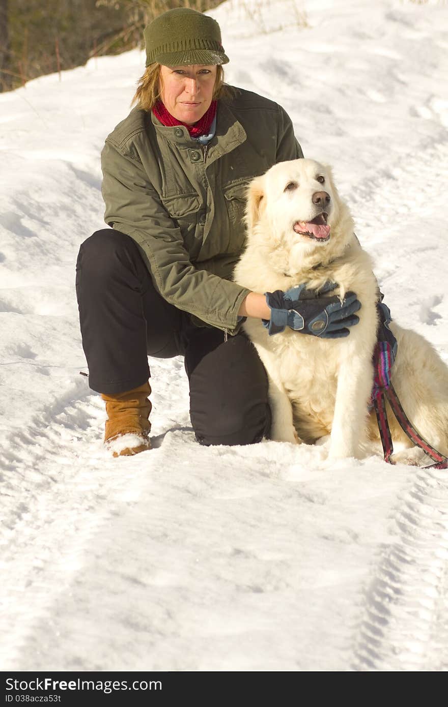 Woman kneeling down with dog at her side in winter. Woman kneeling down with dog at her side in winter.