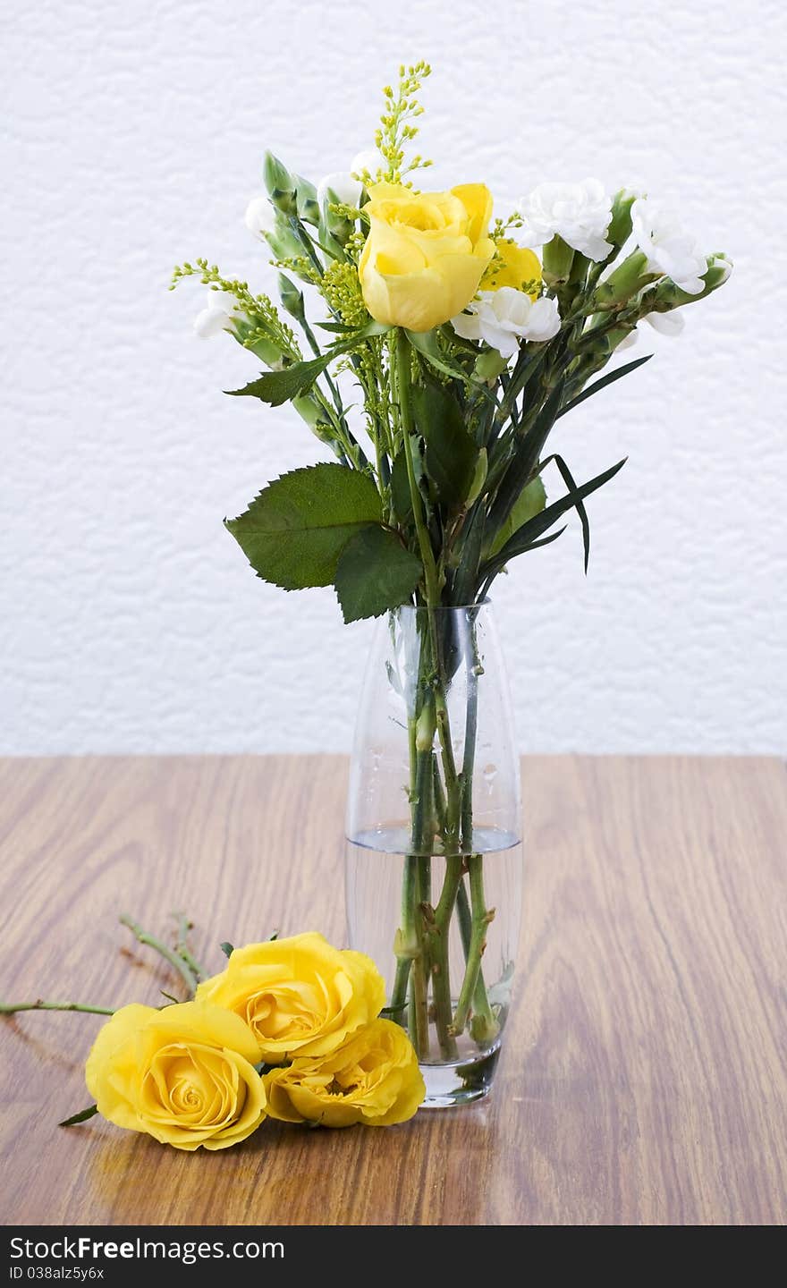 A vase of yellow roses sitting on a table. A vase of yellow roses sitting on a table