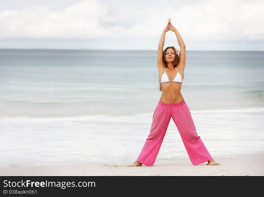 Young woman doing yoga on beach