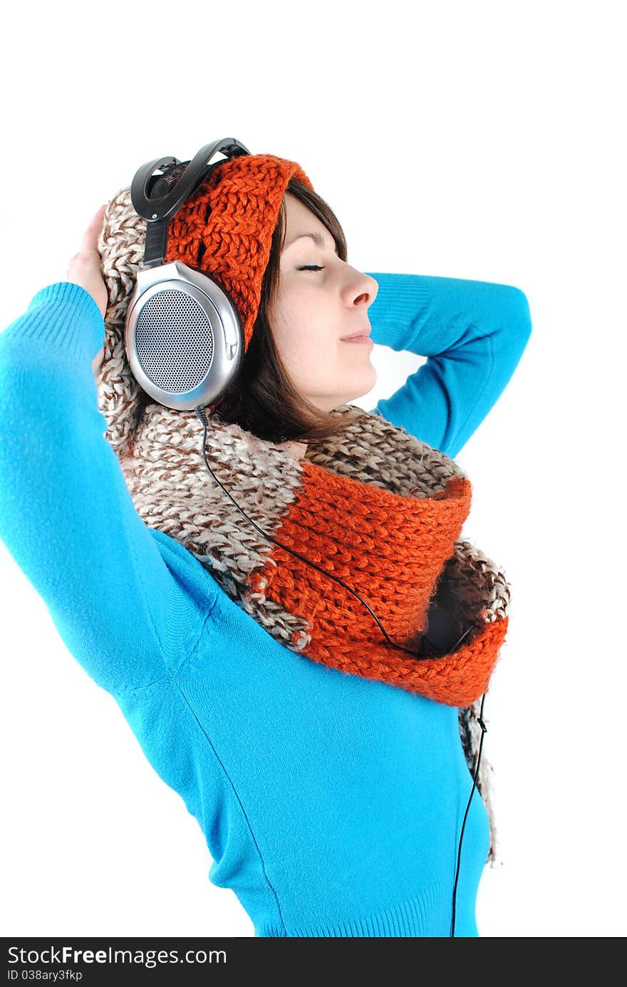 Happy beautiful girl wearing a hat and scarf listening to the music isolated against white background