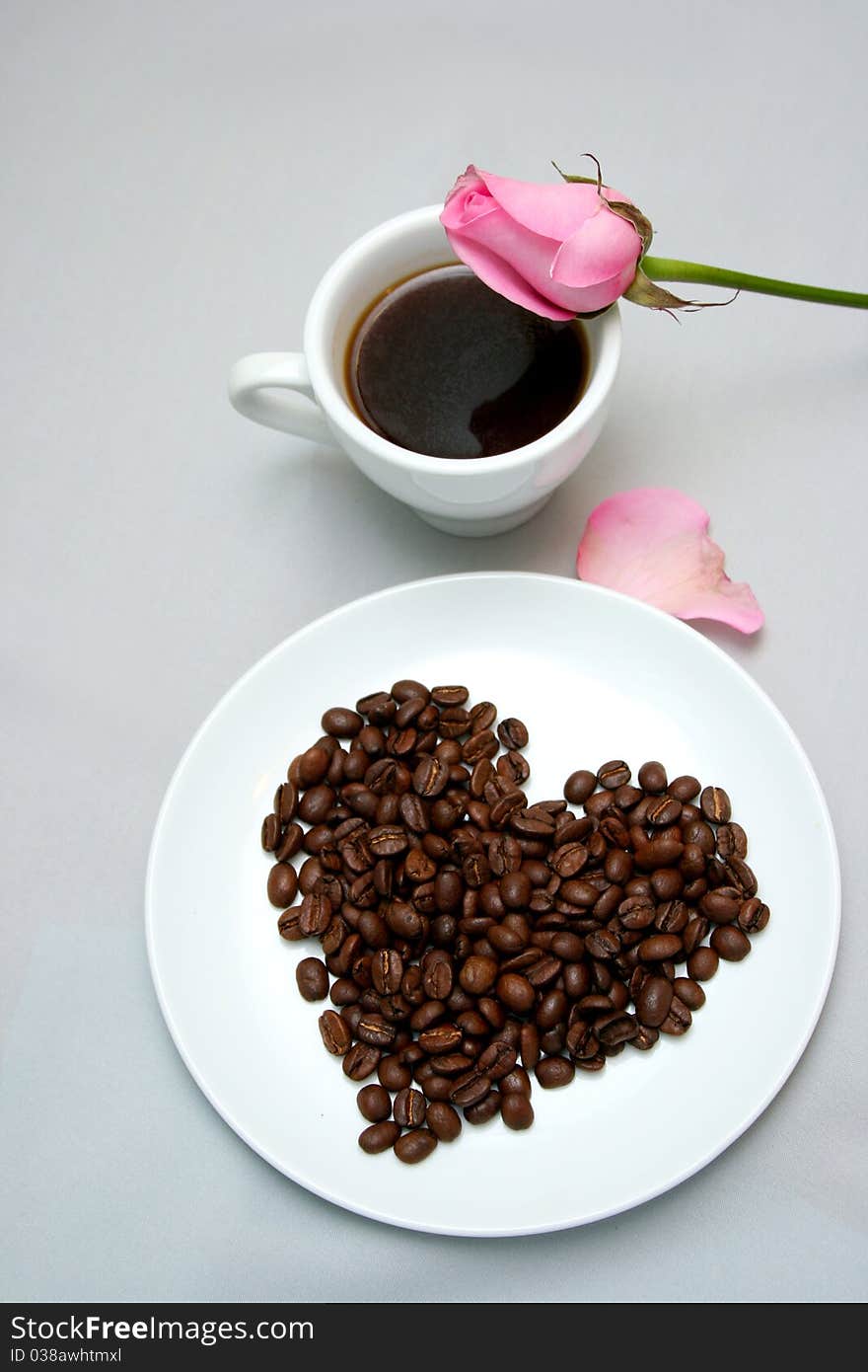 Cup of coffee with heart from coffee beans on grey