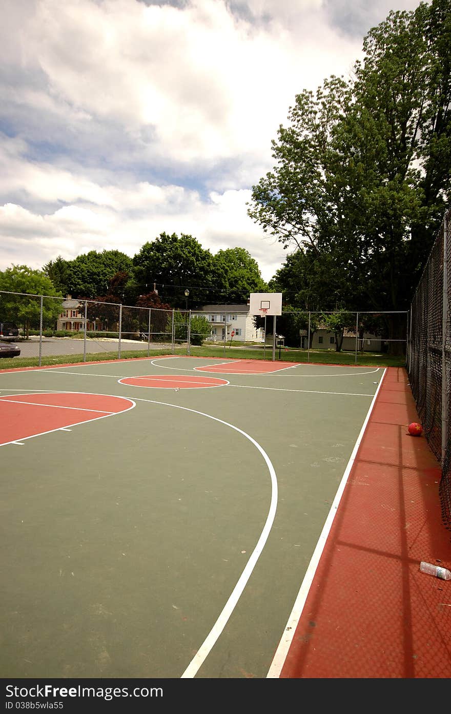 A well-used suburban basketball court, fenced in