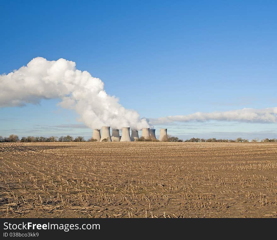 Cooling towers at a power station in the countryside giving off pollution. Cooling towers at a power station in the countryside giving off pollution