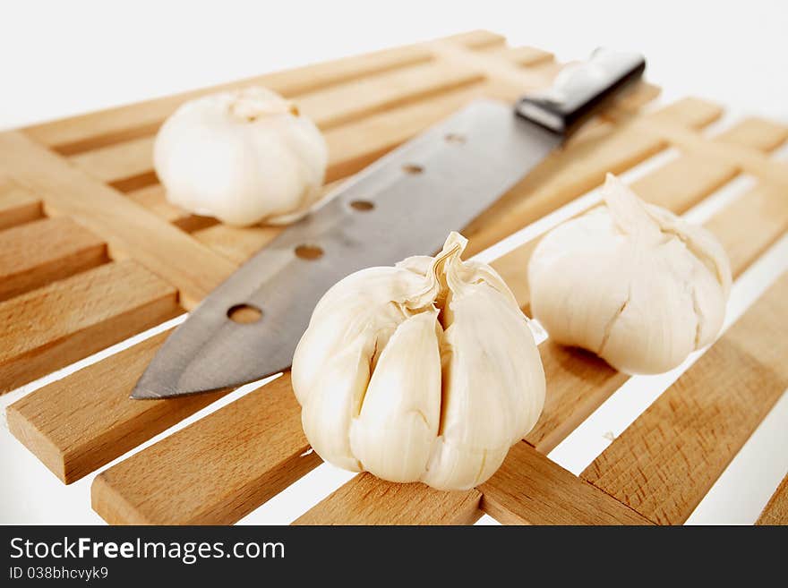 Garlic and knife on a wooden plate. Garlic and knife on a wooden plate