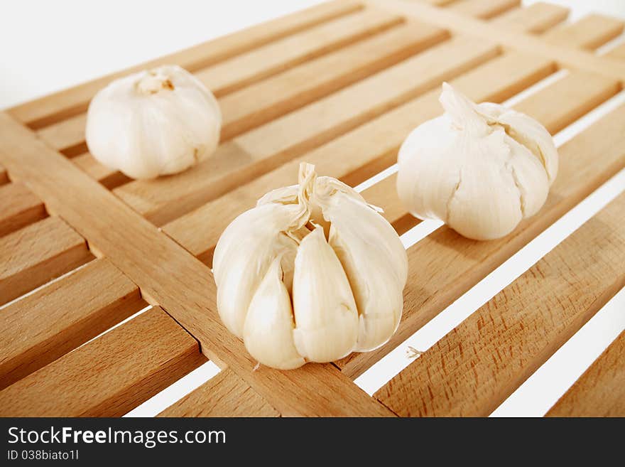 Garlic placed on a wooden plate with the white background