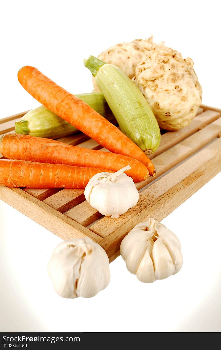 Mix of vegetables on a wooden plate on a white background. Mix of vegetables on a wooden plate on a white background