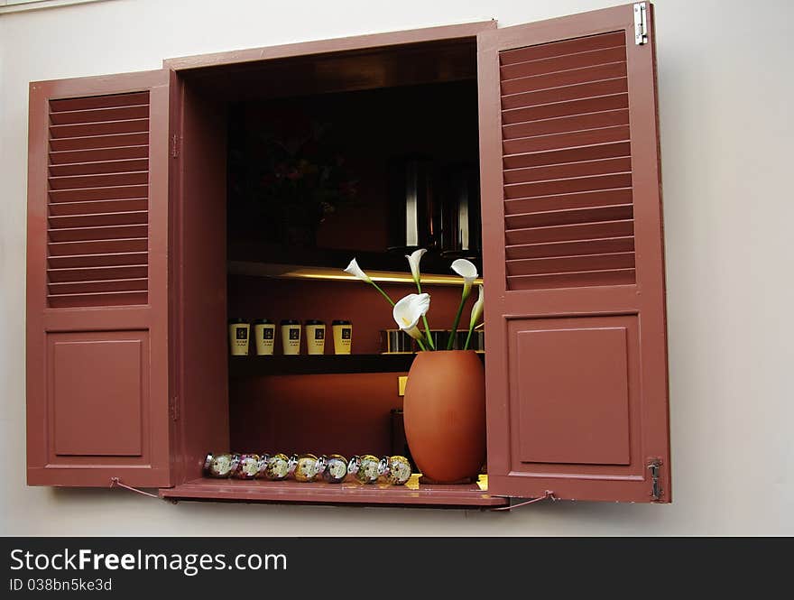 A open window with flowers and coffee cups in it