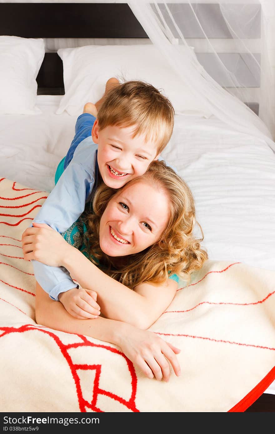 Beautiful young woman holding with a son on a bed. Beautiful young woman holding with a son on a bed