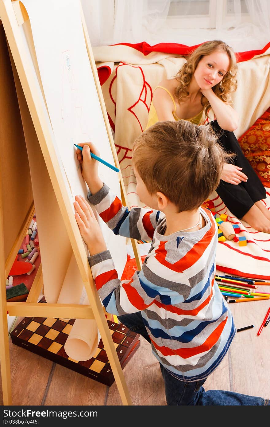 Mother with a son play and draw crayons on the white sheet of paper