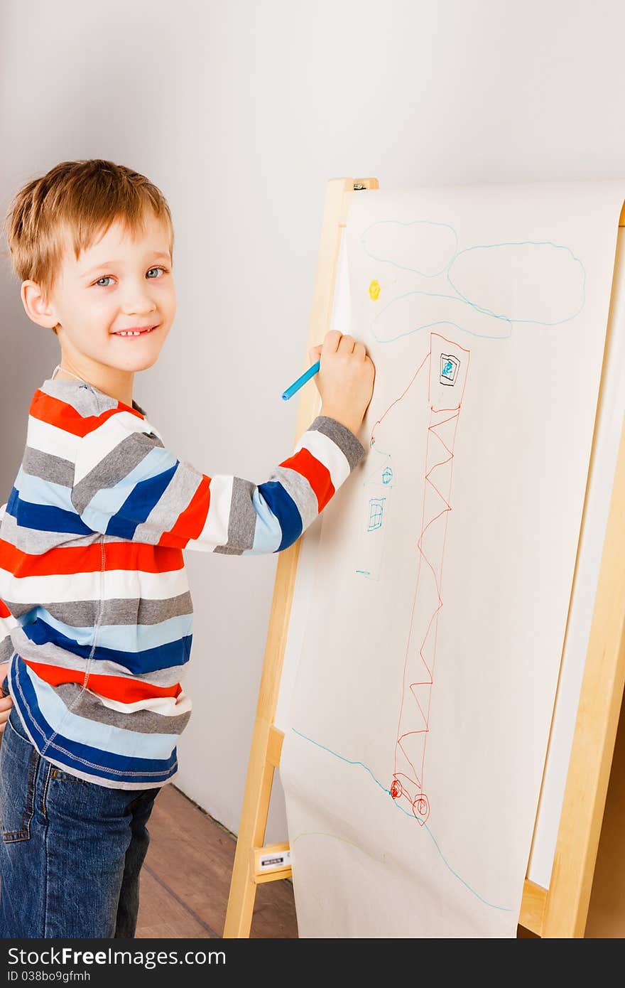 A boy draws crayons on the white sheet of paper