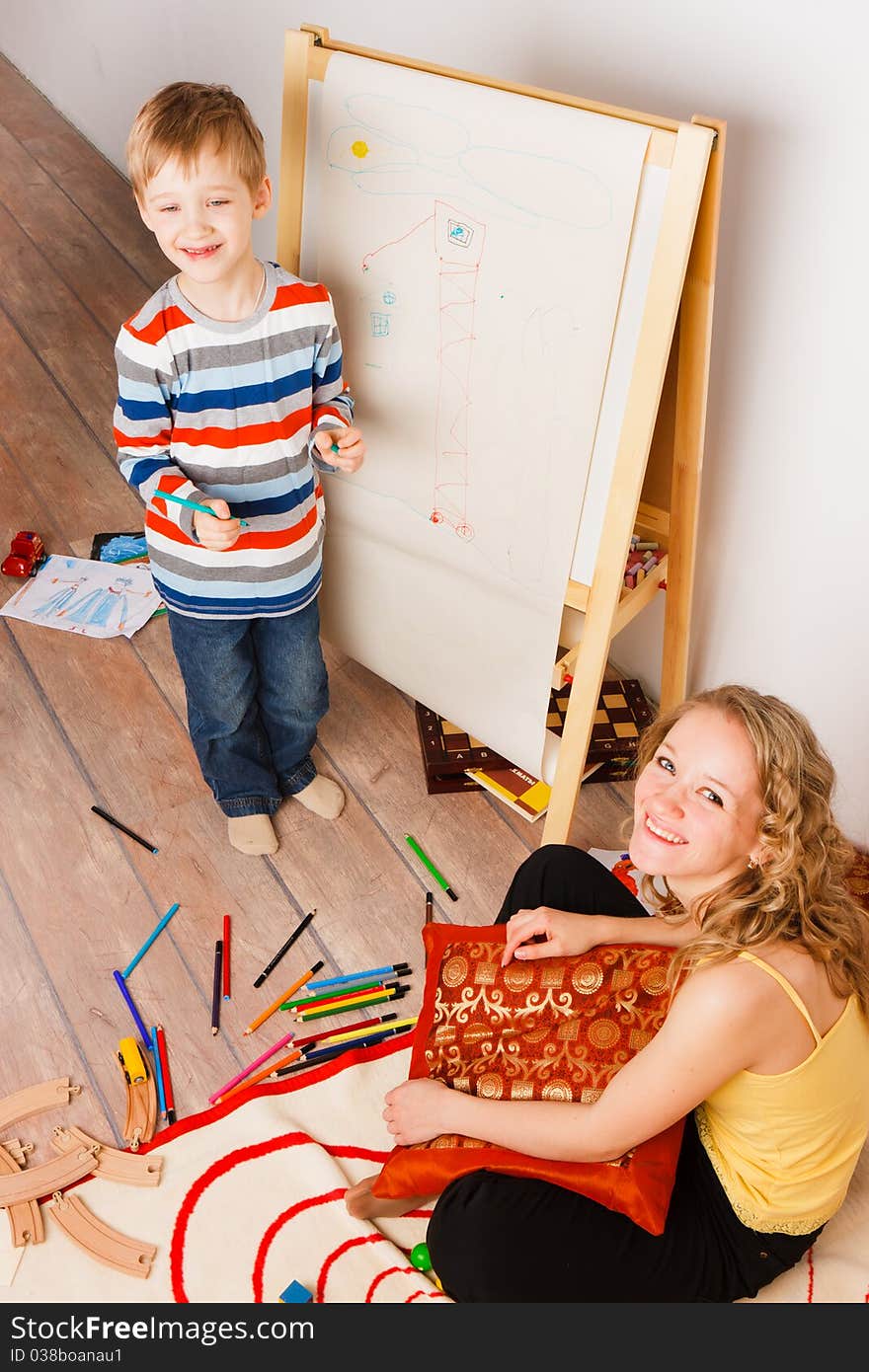 Mother with a son play and draw crayons