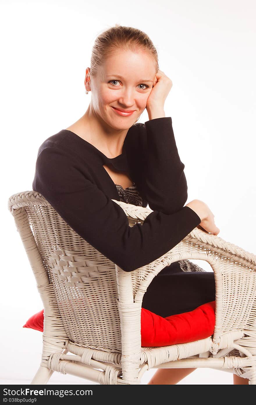 A charming beautiful  woman sits in an arm-chair on a white background