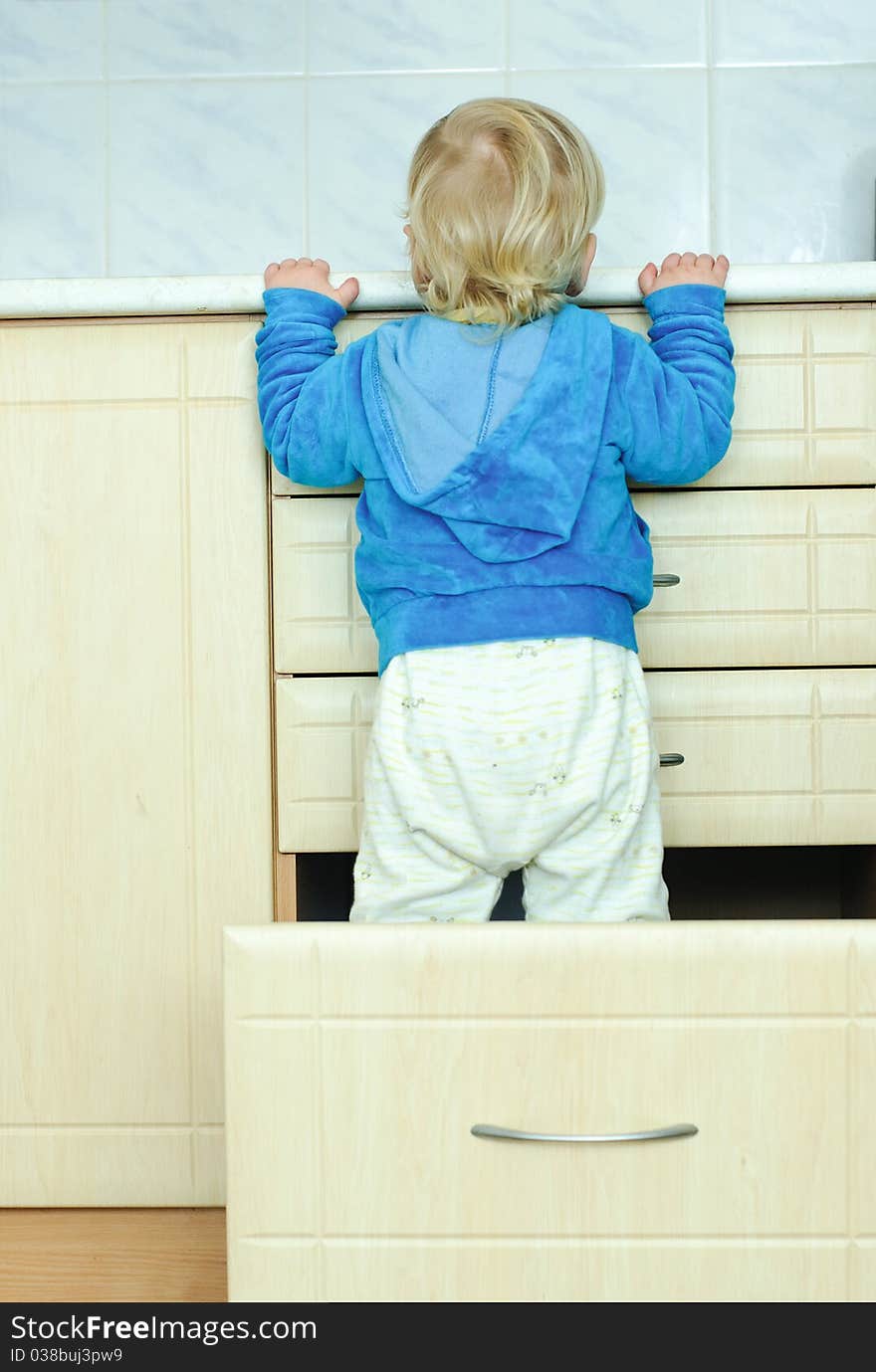 White haired little boy in the kitchen cabinet from the back. White haired little boy in the kitchen cabinet from the back