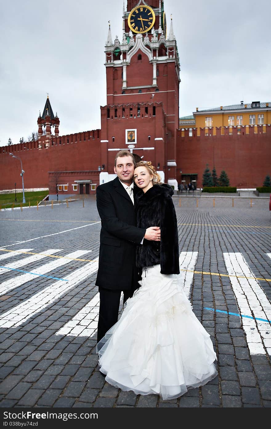 Happy bride and groom on Red Square near the Kremlin's Spassky Tower in Moscow. Happy bride and groom on Red Square near the Kremlin's Spassky Tower in Moscow