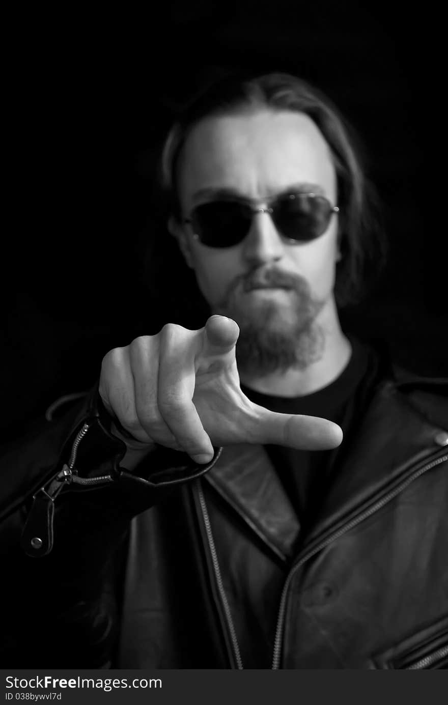 A rock man in sunglasses pointing his finger to the viewer, focus on finger. A rock man in sunglasses pointing his finger to the viewer, focus on finger