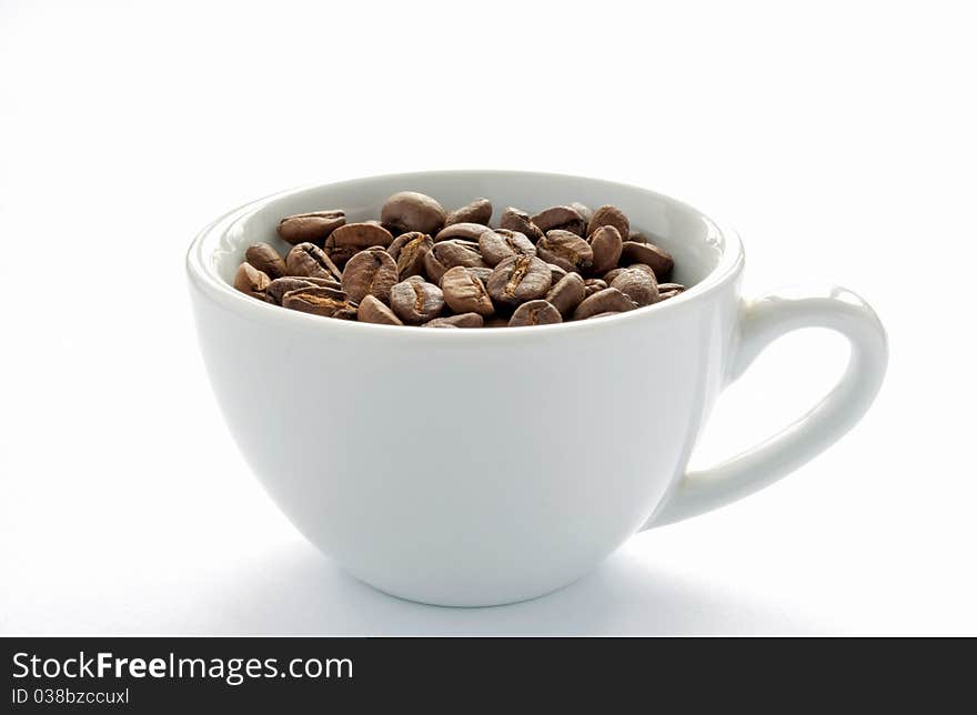 Brown roasted coffee beans in a white cup