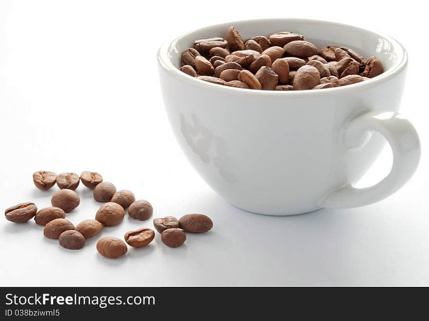 Brown roasted coffee beans in a white cup