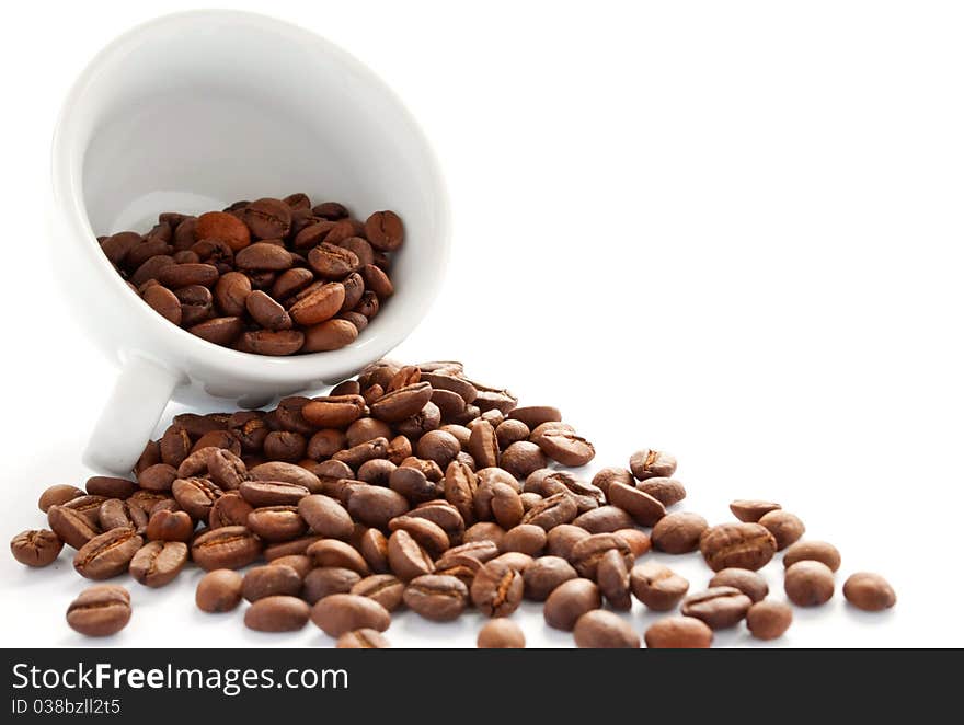 Brown roasted coffee beans in a white cup