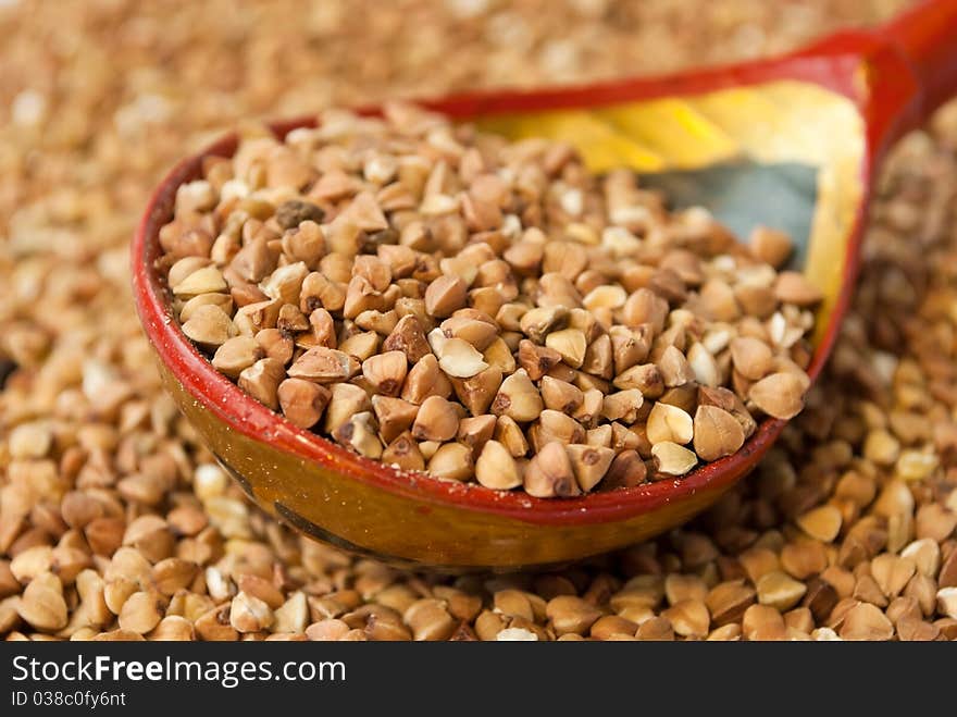 Buckwheat in hohloma spoon over buckwheat background